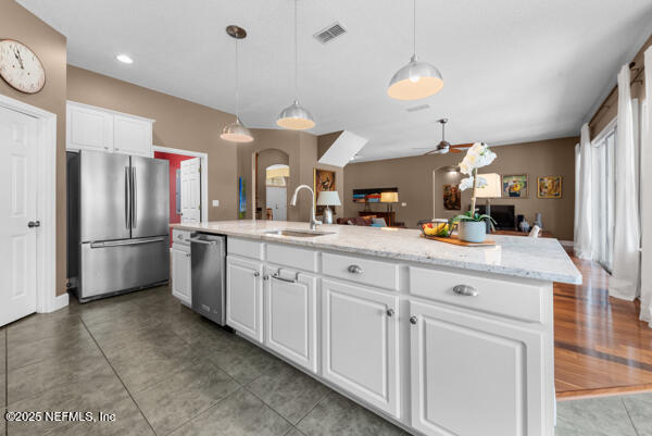 kitchen with a sink, visible vents, white cabinetry, appliances with stainless steel finishes, and open floor plan