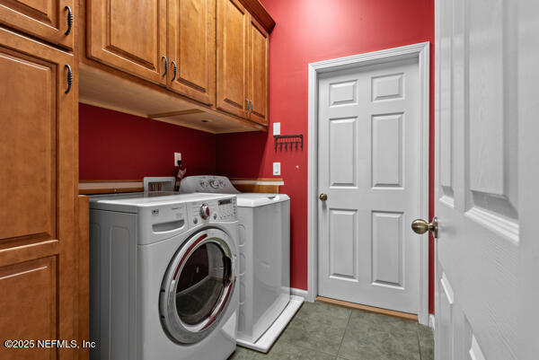 washroom with baseboards, light tile patterned floors, separate washer and dryer, and cabinet space