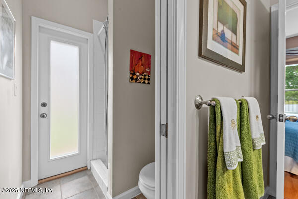 bathroom with baseboards, a stall shower, tile patterned floors, and toilet