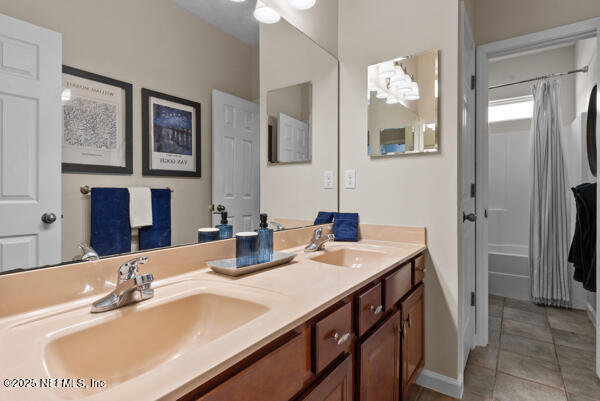 full bathroom featuring double vanity, baseboards, tile patterned flooring, and a sink