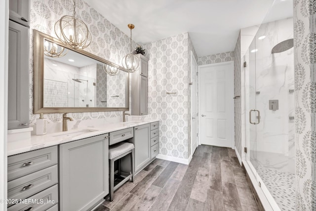 9831 Del Webb Pkwy Unit 1302, Jacksonville, FL 32256 - full bath with wallpapered walls, a chandelier, a marble finish shower, wood finished floors, and double vanity