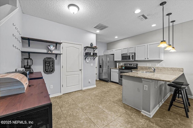 425 Oasis Ln, Orange Park, FL 32073 - kitchen with visible vents, a sink, light stone countertops, a peninsula, and appliances with stainless steel finishes
