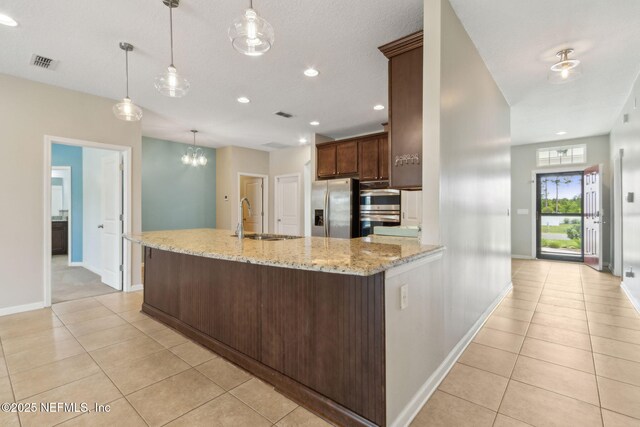 kitchen with a sink, stainless steel appliances, baseboards, light tile patterned floors, and visible vents