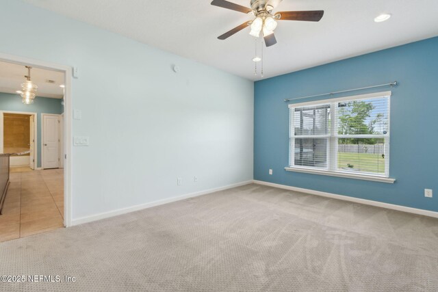 unfurnished room with ceiling fan, light colored carpet, and baseboards