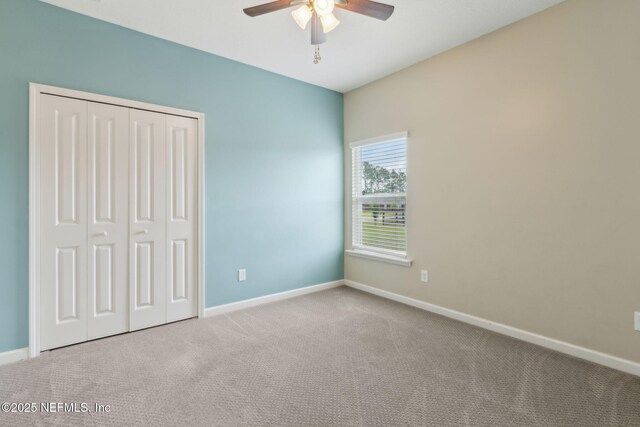 unfurnished bedroom with a closet, baseboards, ceiling fan, and carpet flooring