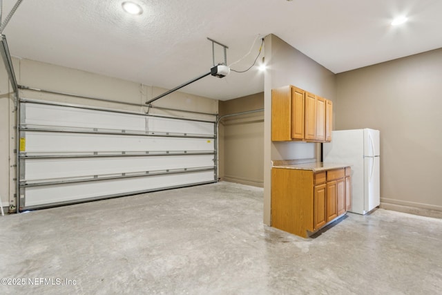 garage featuring freestanding refrigerator, recessed lighting, baseboards, and a garage door opener