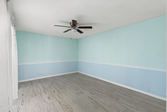 unfurnished room featuring ceiling fan, wood finished floors, and baseboards