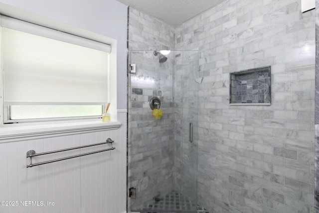 bathroom with wainscoting and a shower stall