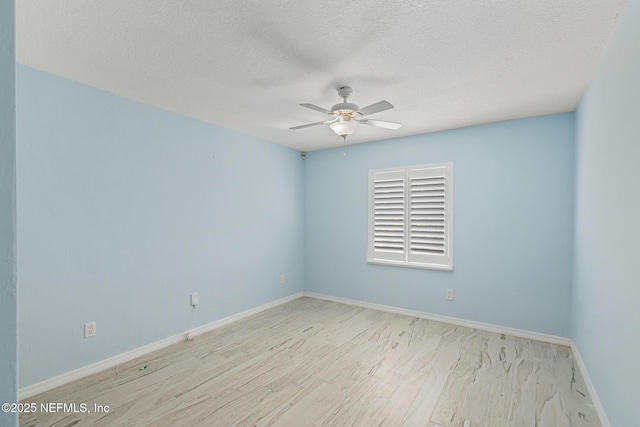 spare room featuring baseboards, wood finished floors, a ceiling fan, and a textured ceiling