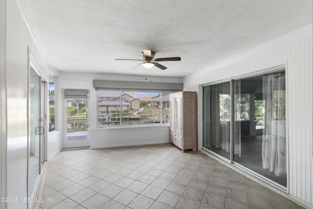 unfurnished sunroom featuring a ceiling fan and plenty of natural light
