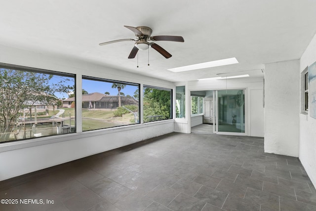 unfurnished sunroom with a ceiling fan and a skylight