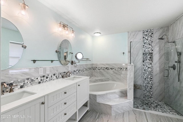 bathroom featuring double vanity, a garden tub, a stall shower, and a sink