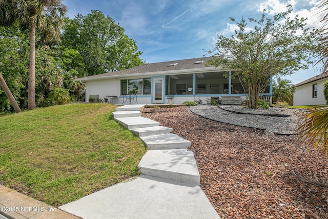 view of front of property with a shingled roof, a front lawn, a sunroom, and stucco siding