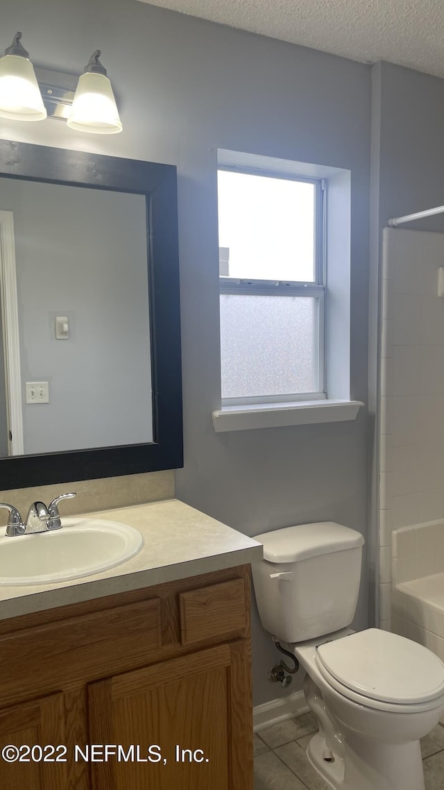 bathroom with vanity, toilet, a textured ceiling, baseboards, and tile patterned flooring