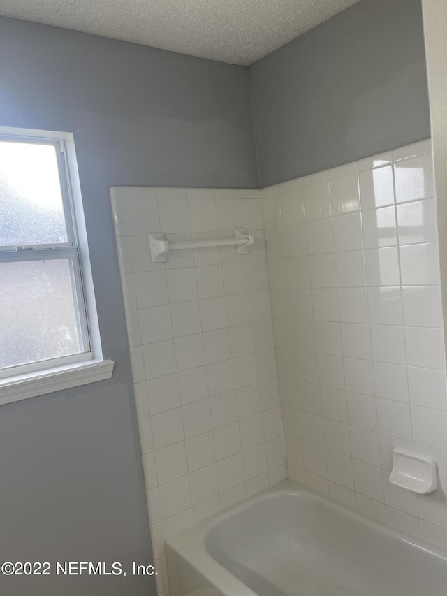 full bath with a textured ceiling and shower / bathing tub combination
