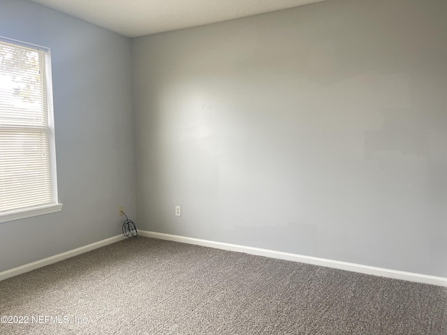 carpeted empty room featuring baseboards