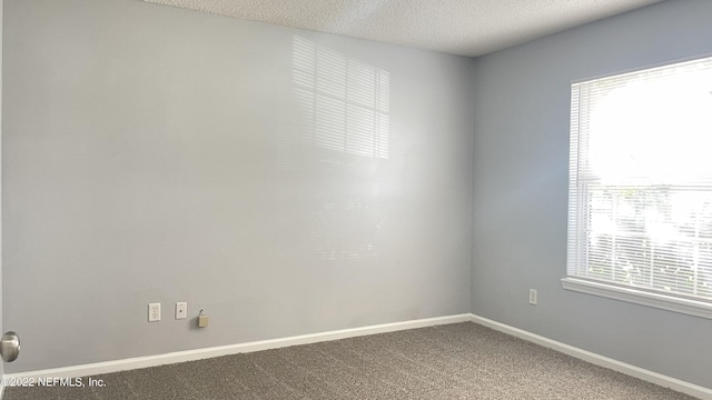 carpeted spare room with a textured ceiling and baseboards