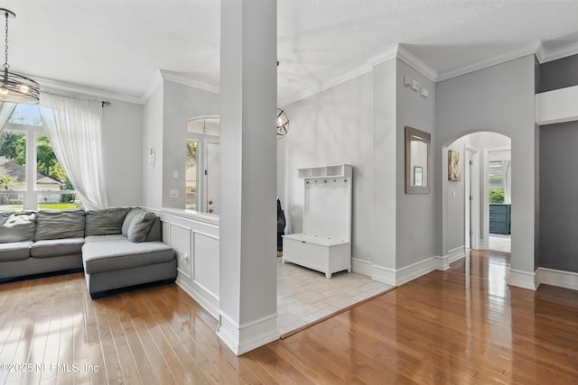 living room featuring wood-type flooring, arched walkways, and ornamental molding