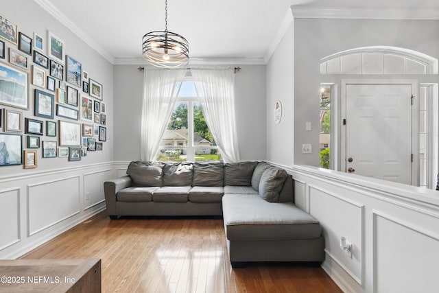 living area with wood-type flooring, a decorative wall, and ornamental molding