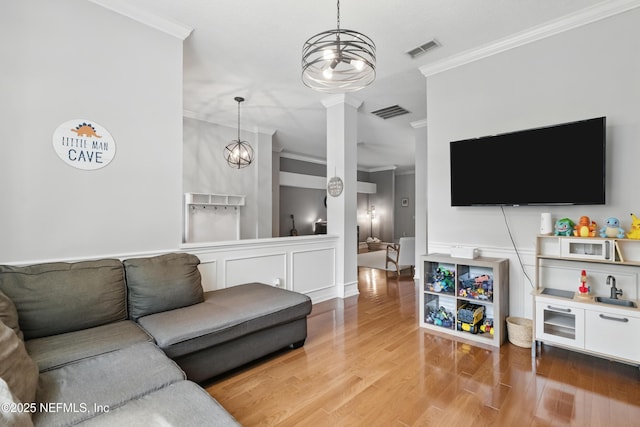 living area with ornamental molding, wood finished floors, and visible vents