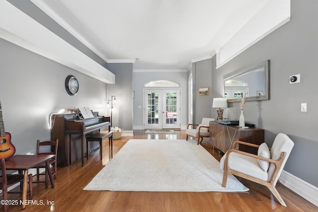 living area with baseboards, crown molding, french doors, and wood finished floors