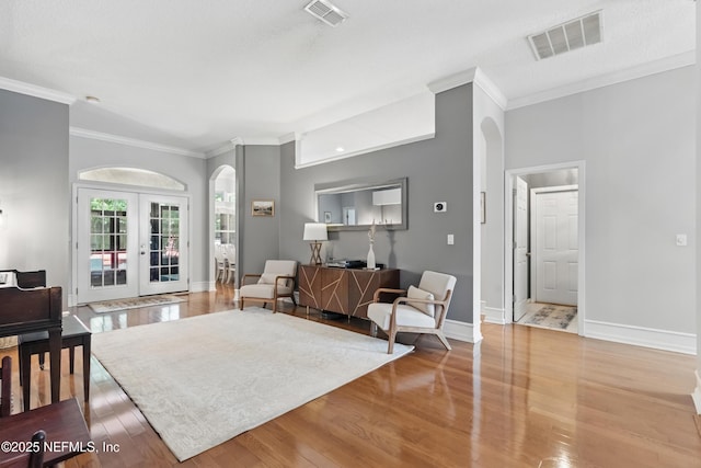 living room featuring arched walkways, visible vents, and ornamental molding