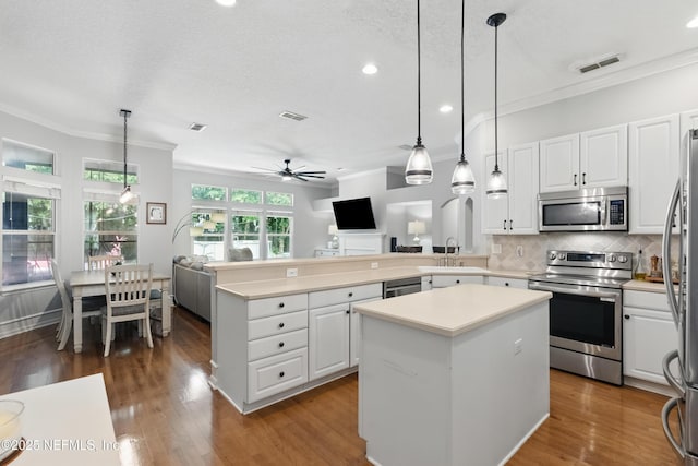 kitchen with ceiling fan, crown molding, stainless steel appliances, and visible vents