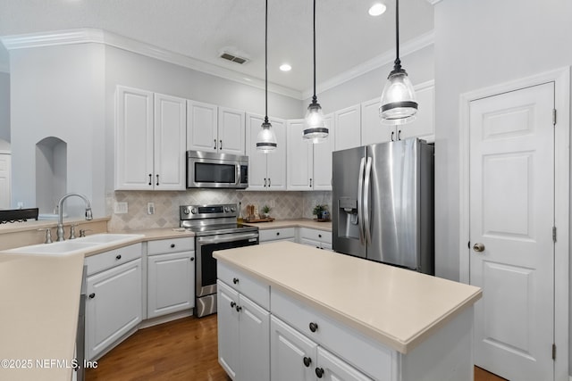 kitchen featuring visible vents, ornamental molding, a sink, decorative backsplash, and appliances with stainless steel finishes