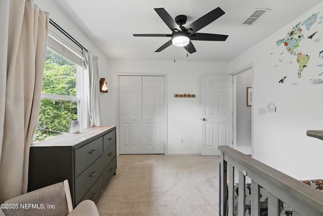 bedroom with baseboards, visible vents, light colored carpet, a ceiling fan, and a closet
