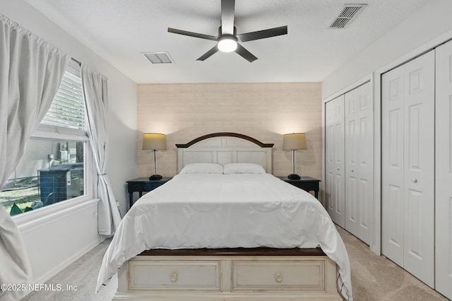 bedroom with visible vents, carpet flooring, and multiple closets