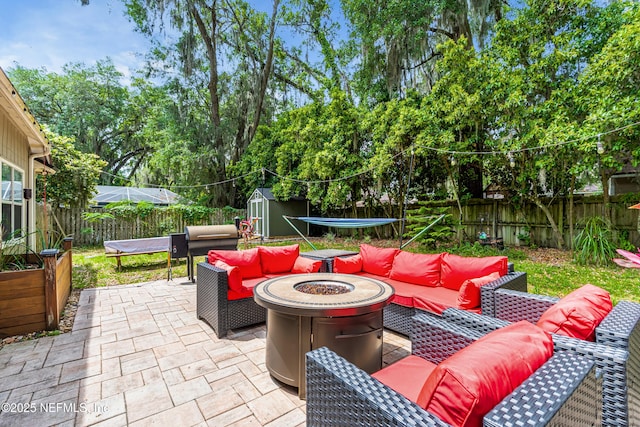 view of patio with a trampoline, an outdoor living space with a fire pit, a fenced backyard, and a storage shed