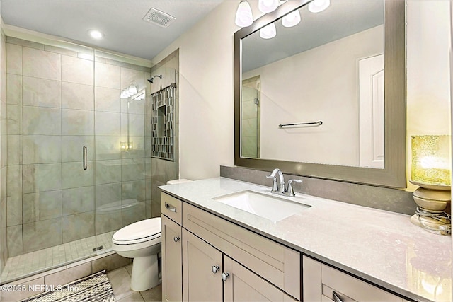 bathroom featuring toilet, vanity, visible vents, and a stall shower