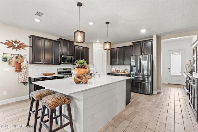 kitchen with decorative backsplash, wood finish floors, appliances with stainless steel finishes, and baseboards
