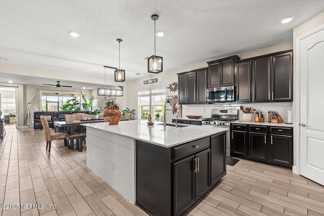 kitchen featuring light countertops, backsplash, a sink, light wood-type flooring, and appliances with stainless steel finishes