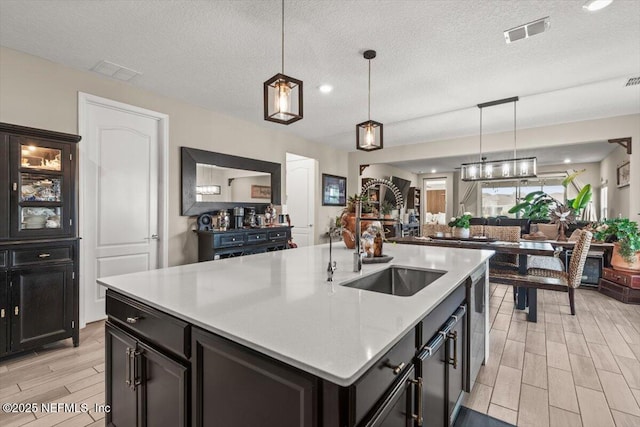 kitchen with light countertops, visible vents, a sink, wood finish floors, and open floor plan