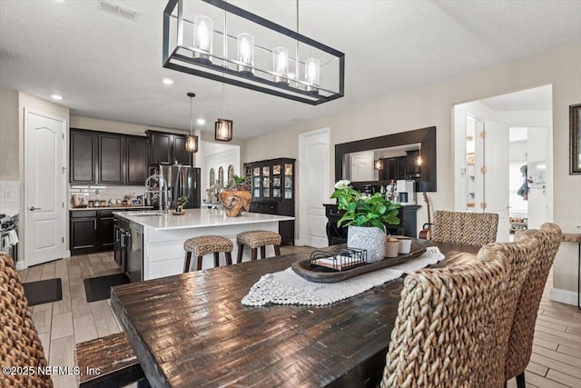 dining room featuring recessed lighting, wood tiled floor, visible vents, and a textured ceiling