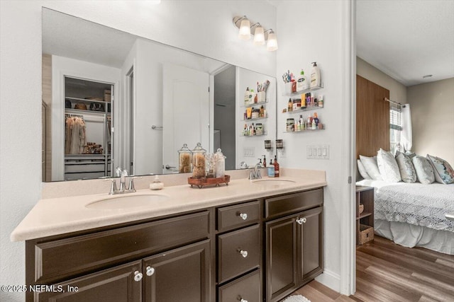 full bath with double vanity, wood finished floors, ensuite bathroom, and a sink