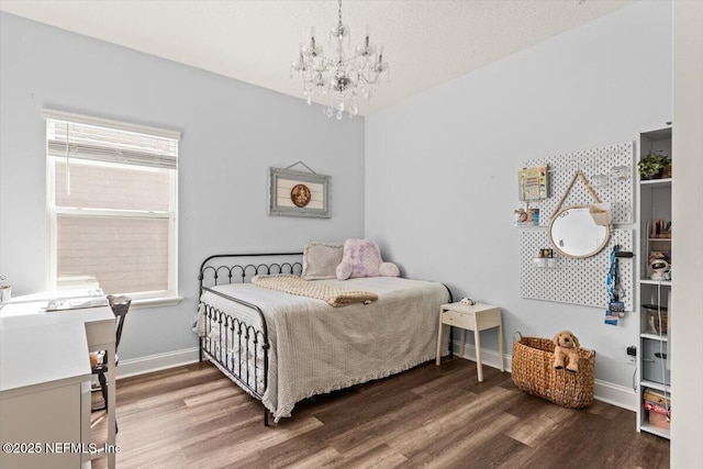 bedroom with baseboards, wood finished floors, and a notable chandelier