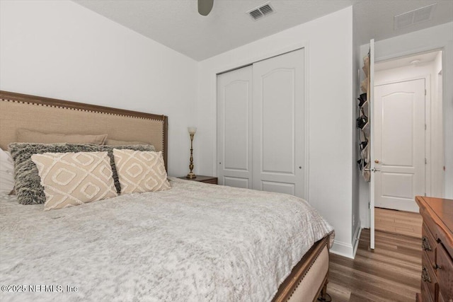bedroom with a closet, visible vents, baseboards, and dark wood-style flooring
