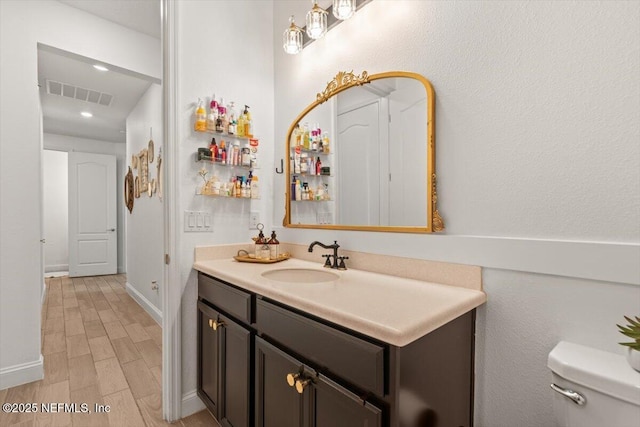 bathroom with recessed lighting, wood finished floors, visible vents, toilet, and vanity