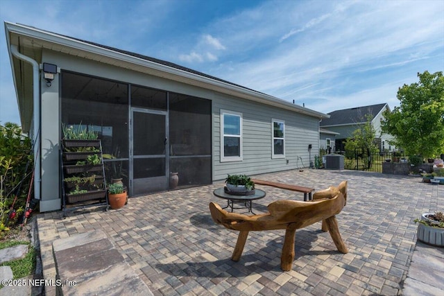 view of patio / terrace featuring fence, a sunroom, and central AC