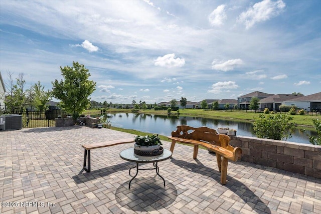 view of patio featuring central air condition unit, fence, and a water view