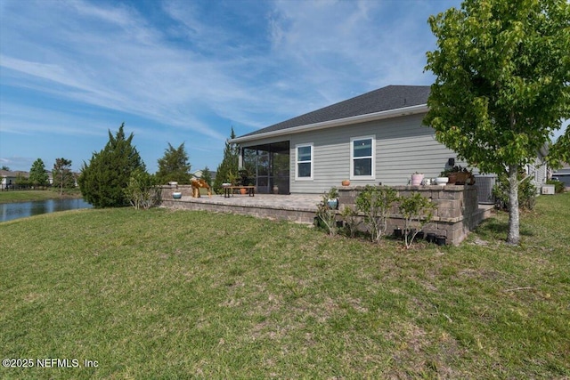 rear view of house with a lawn, central AC unit, a patio, and a water view