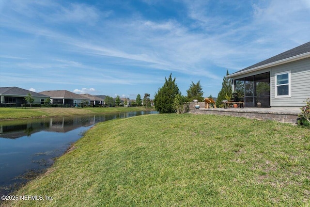 view of yard featuring a sunroom and a water view