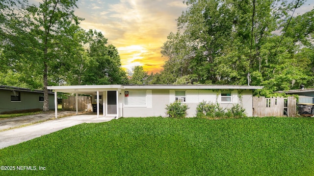 single story home featuring a yard, fence, driveway, and a carport