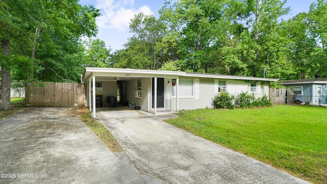 ranch-style house featuring fence, a front lawn, concrete driveway, concrete block siding, and an attached carport