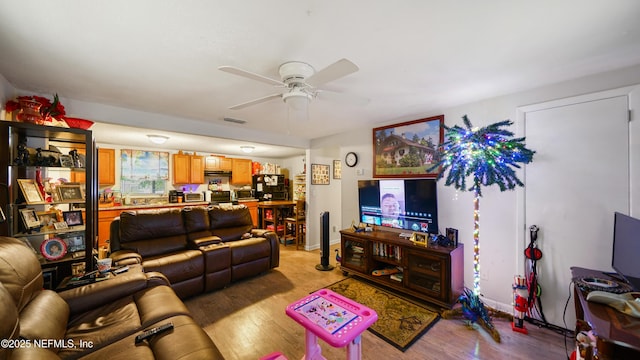 living area featuring ceiling fan, visible vents, baseboards, and light wood-style floors
