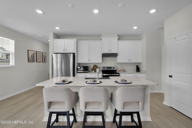 143 Bayard Pl, Jacksonville, FL 32259 - kitchen with under cabinet range hood, stainless steel appliances, a center island with sink, and a breakfast bar area