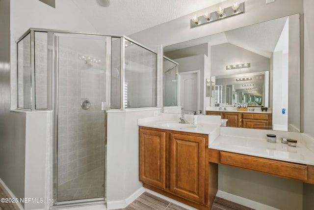 bathroom with vaulted ceiling, vanity, and a shower stall