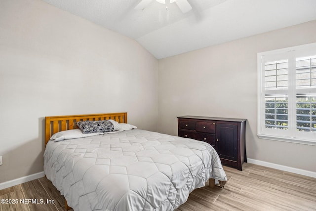 bedroom featuring lofted ceiling, baseboards, wood finished floors, and ceiling fan